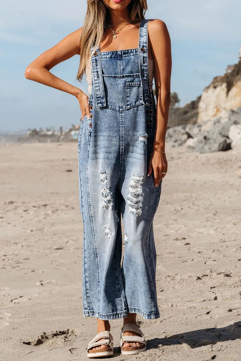 Person wearing denim overalls on a beach