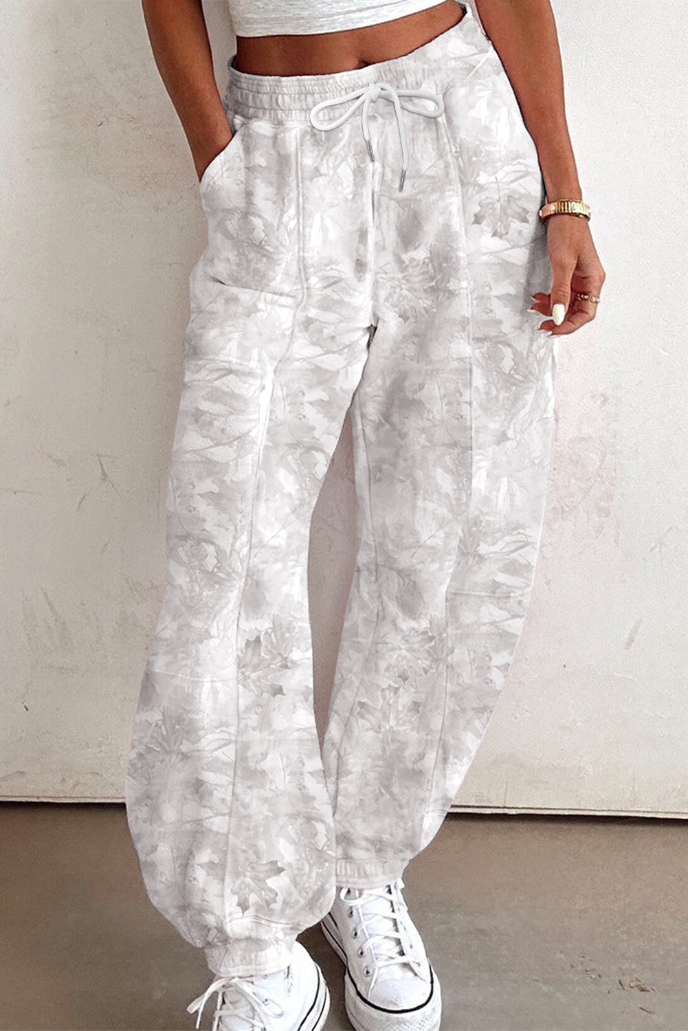 Person wearing white floral pants with a plain background