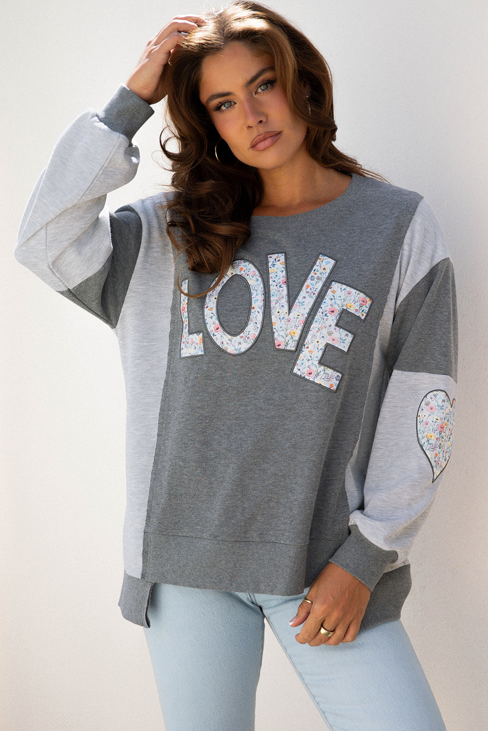 Woman wearing a gray sweatshirt with 'LOVE' printed on it against a plain background