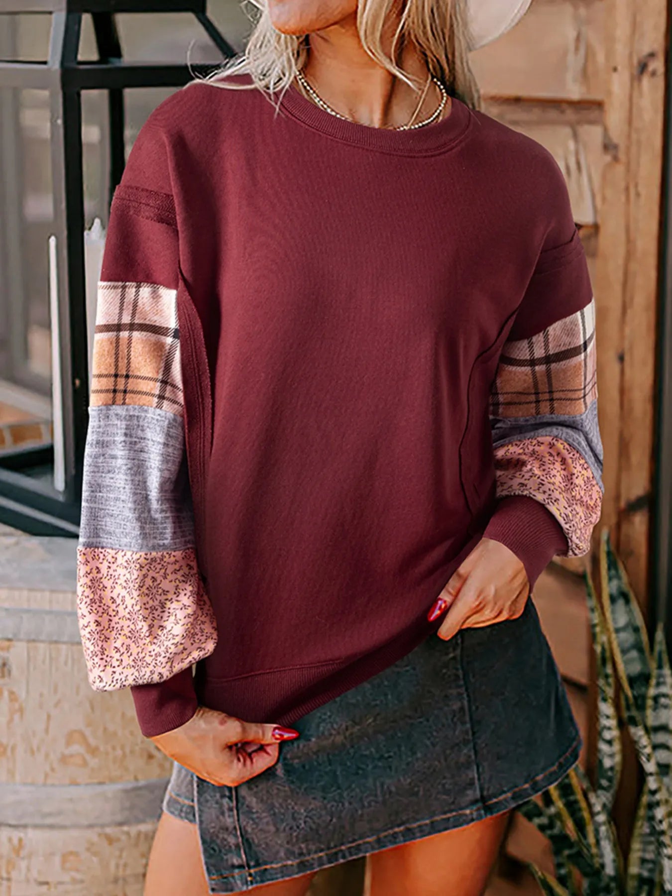 Person wearing a maroon sweater with plaid sleeves in an outdoor setting