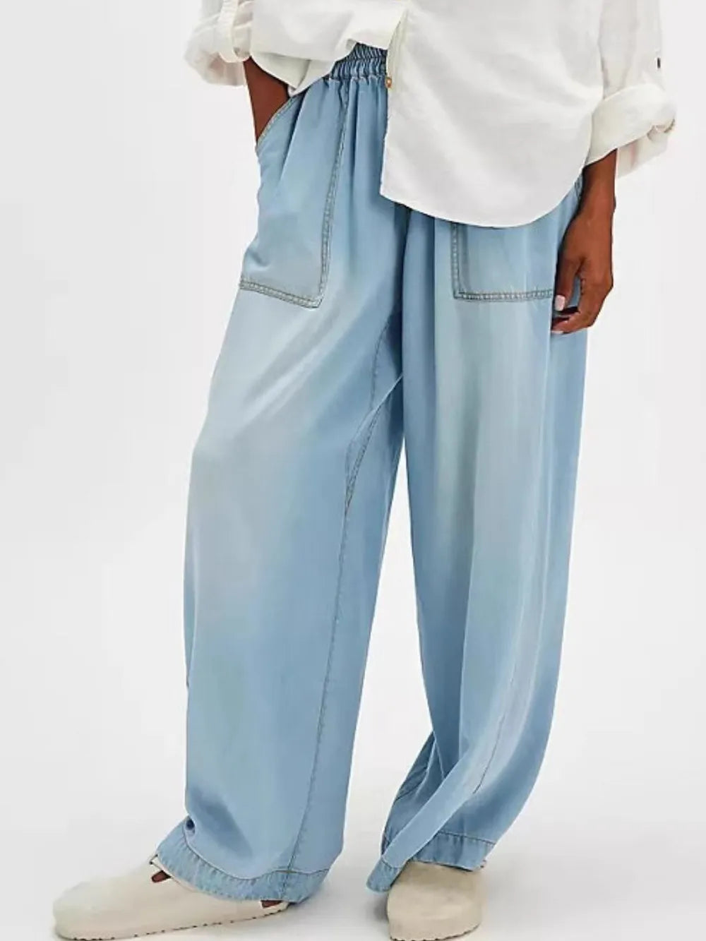 Light blue wide-leg jeans worn with a white shirt on a light gray background