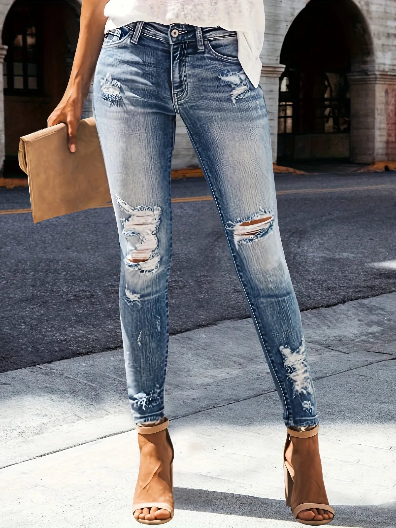 Person wearing distressed blue jeans with a blurred background