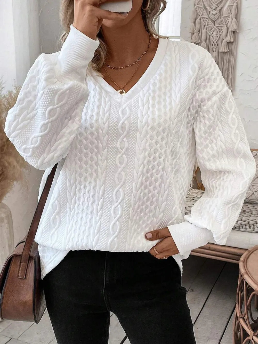 Person wearing a white cable knit sweater and black pants