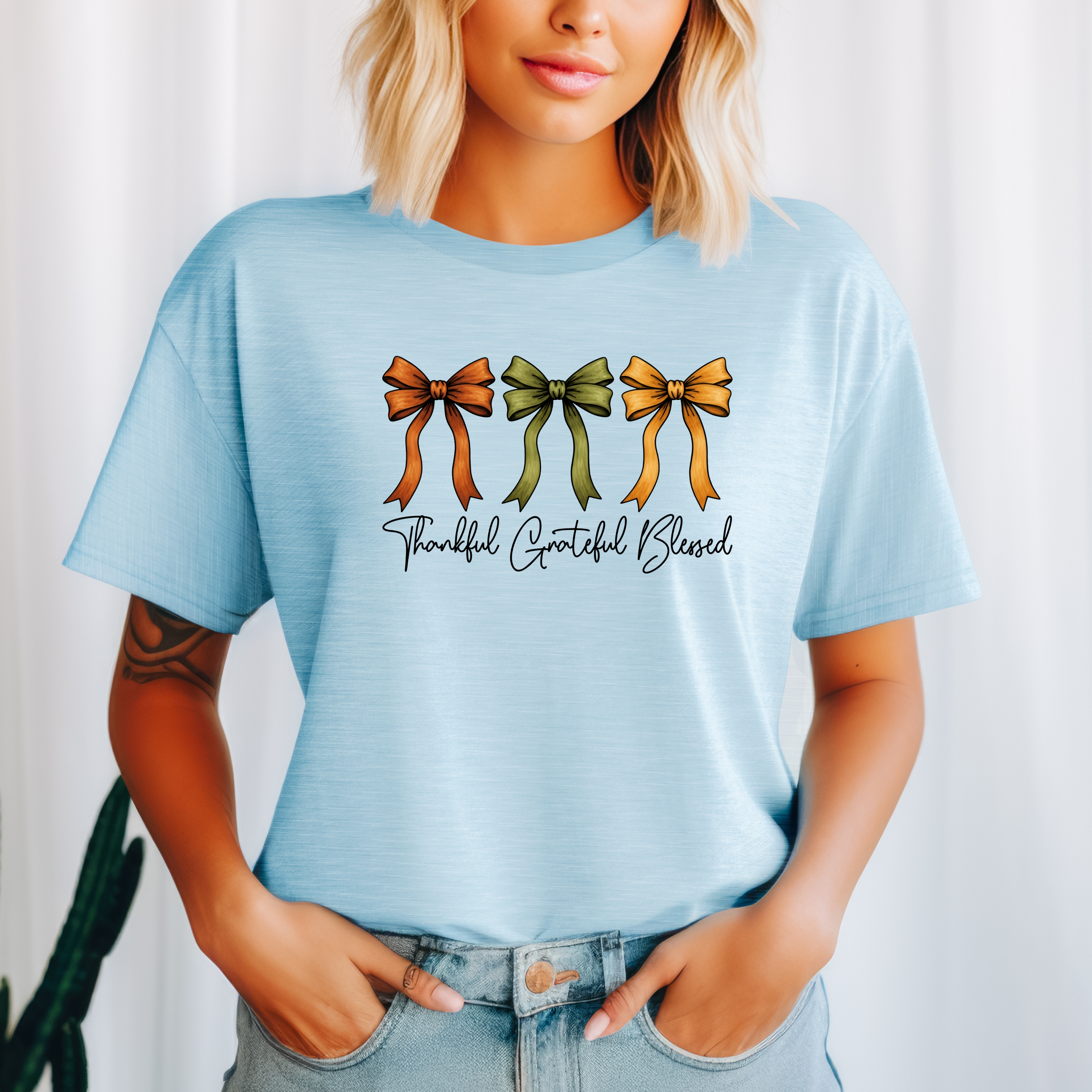 Person wearing a light blue t-shirt with colorful bows and text on a white background