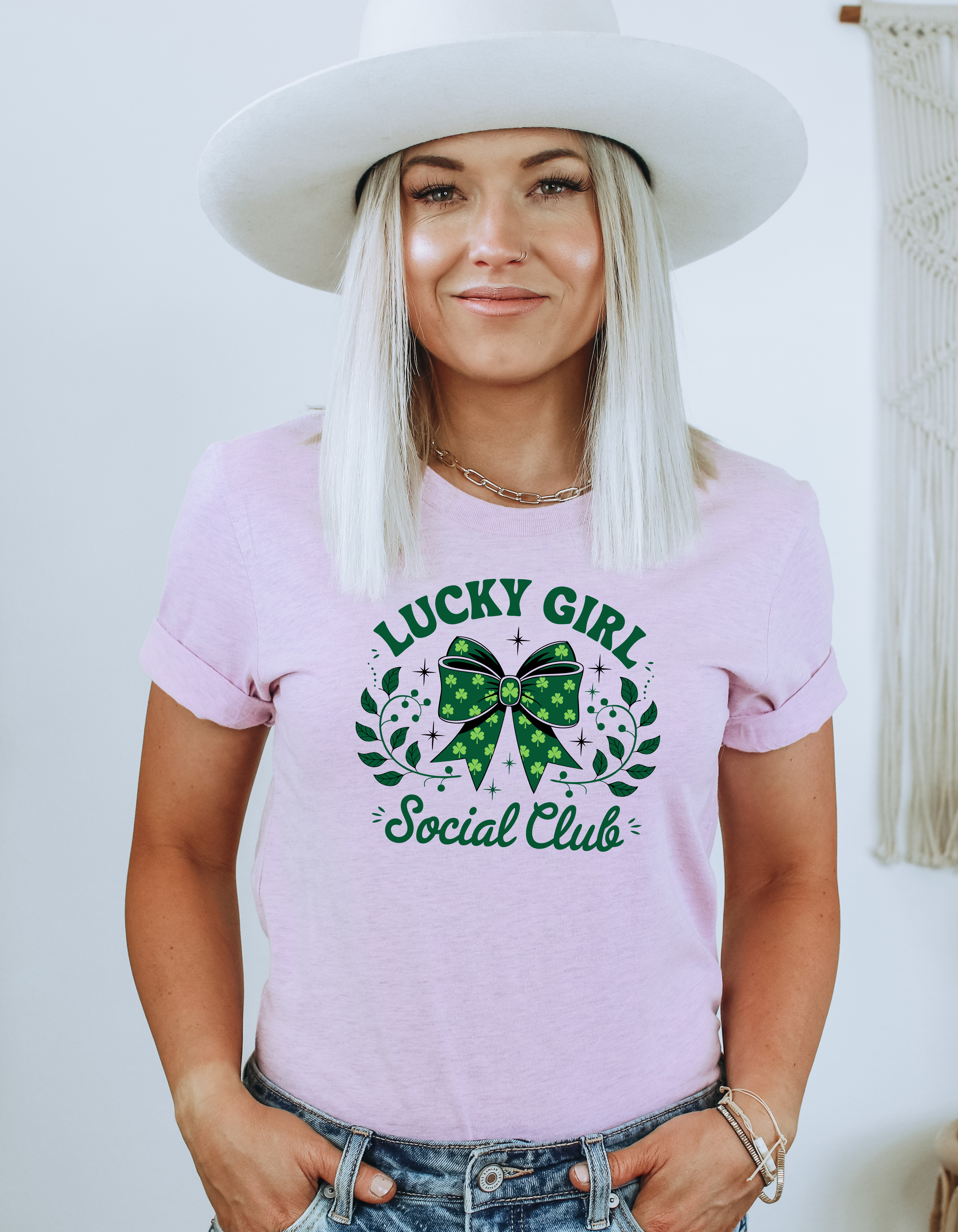 Woman wearing a pink t-shirt with 'Lucky Girl Social Club' design, white background